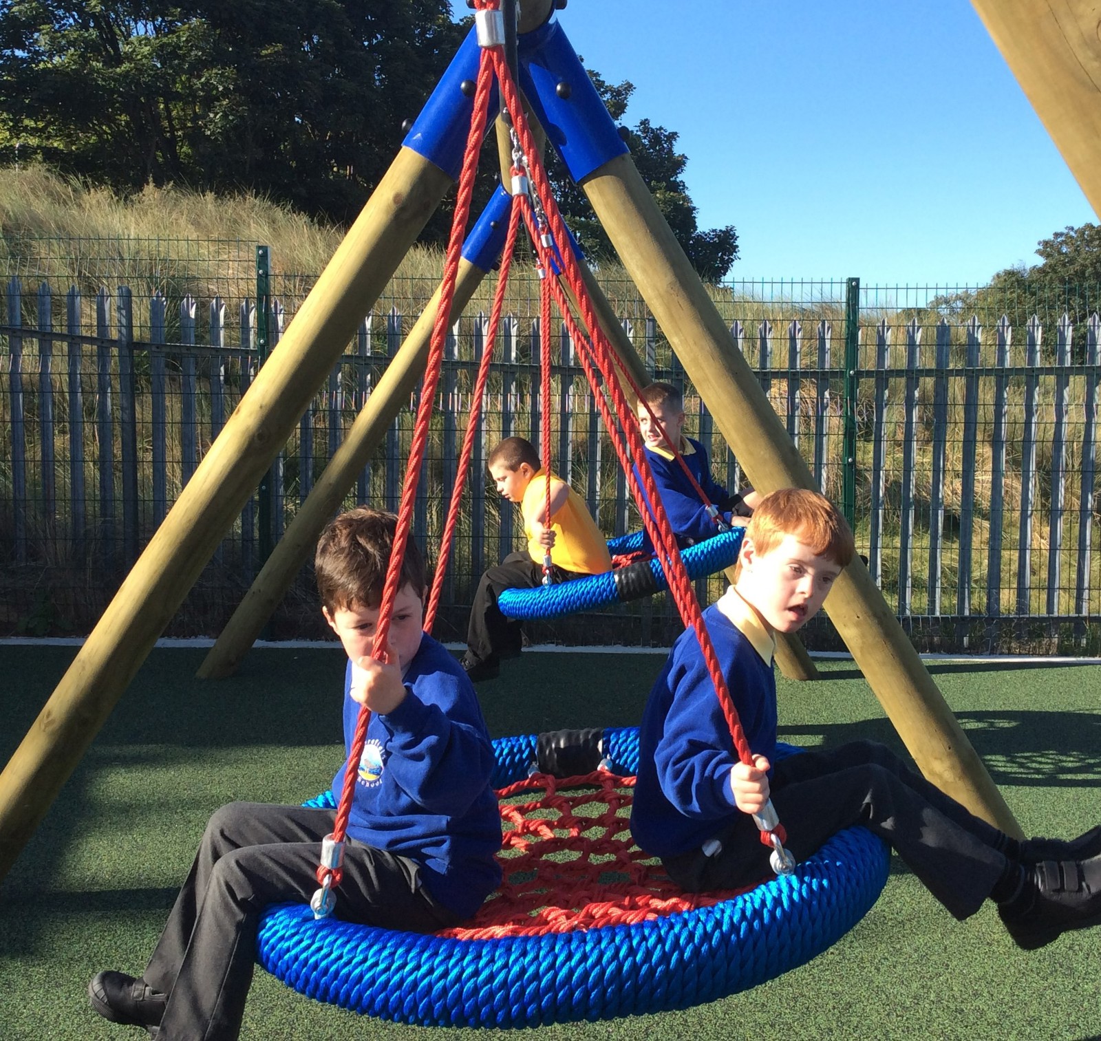 Two school boys sitting on a swing in the playground at Merefield School