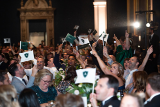 People cheering and waving flags in the dining room of the Spotlight Awards event