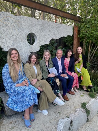 Members of the ACT team and Group colleagues with John Tiner, Chairman of ACT and The Ardonagh Group, seated on one of the 'listening benches' places throughout the garden.