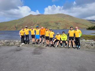 The Ride4Life team stood together in front of a lake and a hill, taking a break during their ride