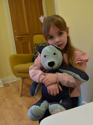 A little girl with her teddy receiving support at Foyle hospice.