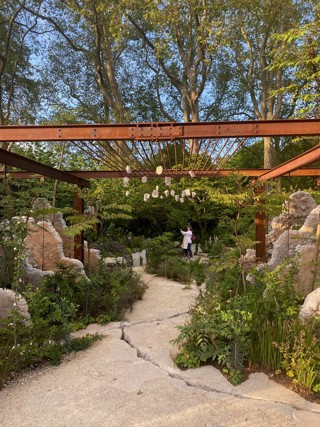 View of the Samaritans' Listening Garden, including the planting and a steel archway at the garden's entrance - looking through to flowers and a bench at the back.