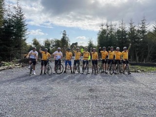The Ride4Life team stood together by the site of Daisy Lodge, surrounded by trees