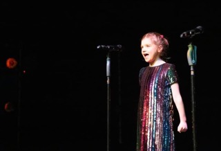 Lucia singing on stage in a show.