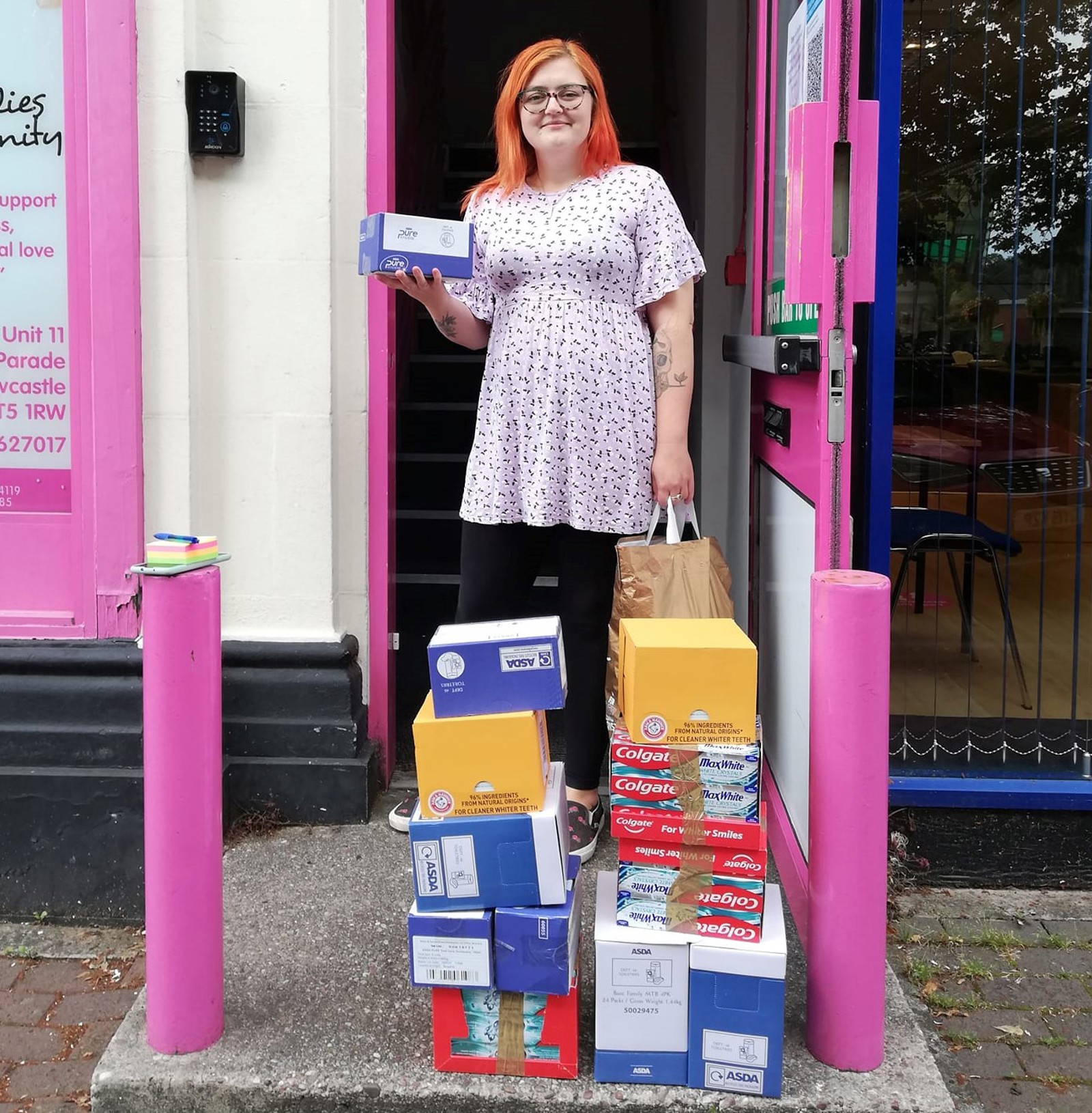 Woman stood in front of a shop with period product donations.